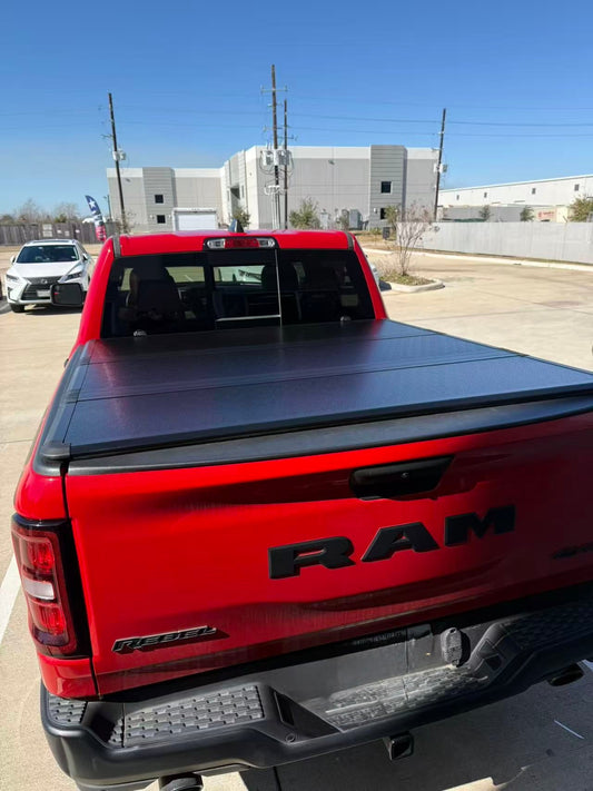 Closed hard tri-fold tonneau cover on a red RAM pickup truck