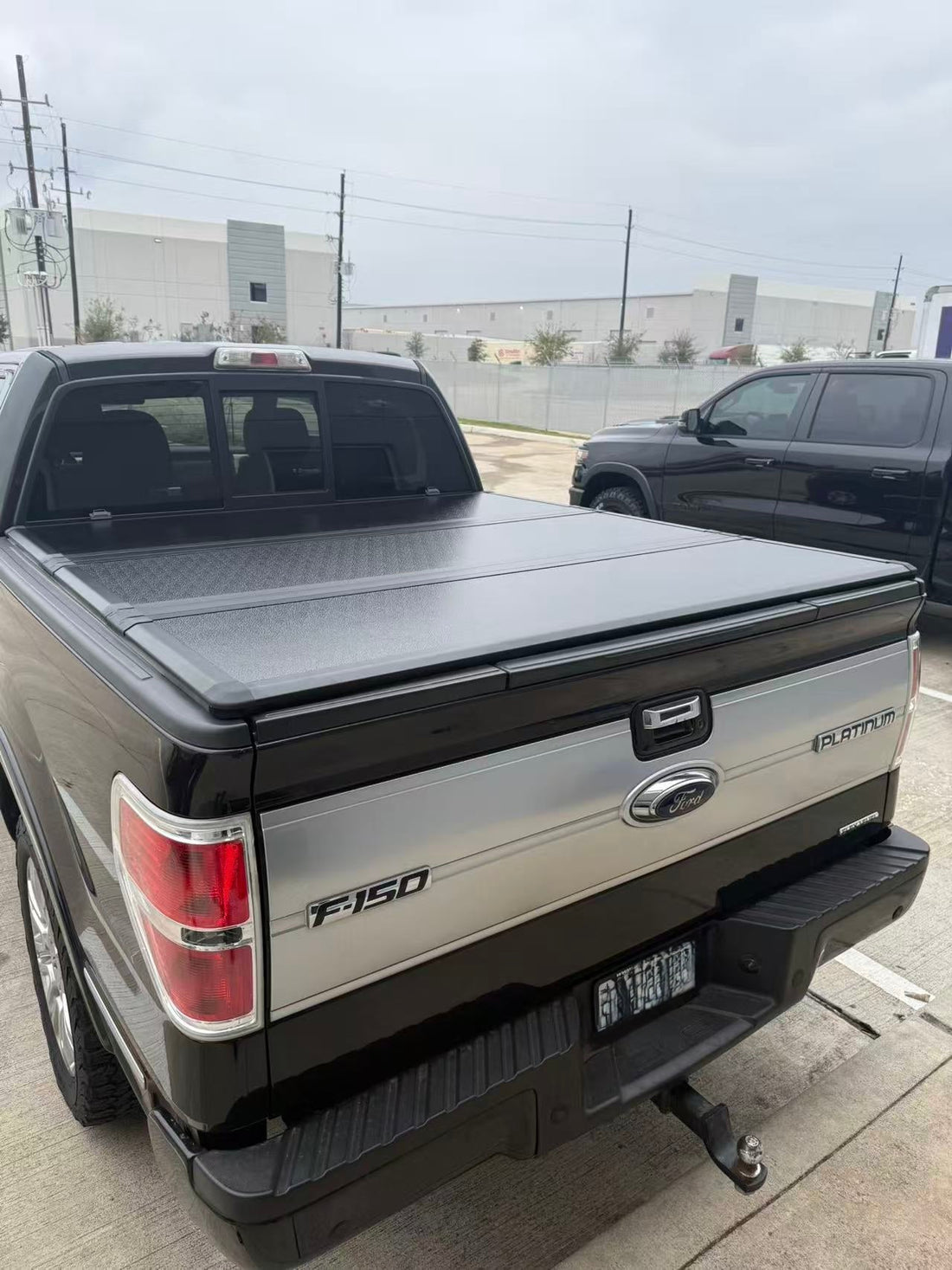 Hard tri-fold tonneau cover fitted along the bed rails of a light-colored Ford pickup truck